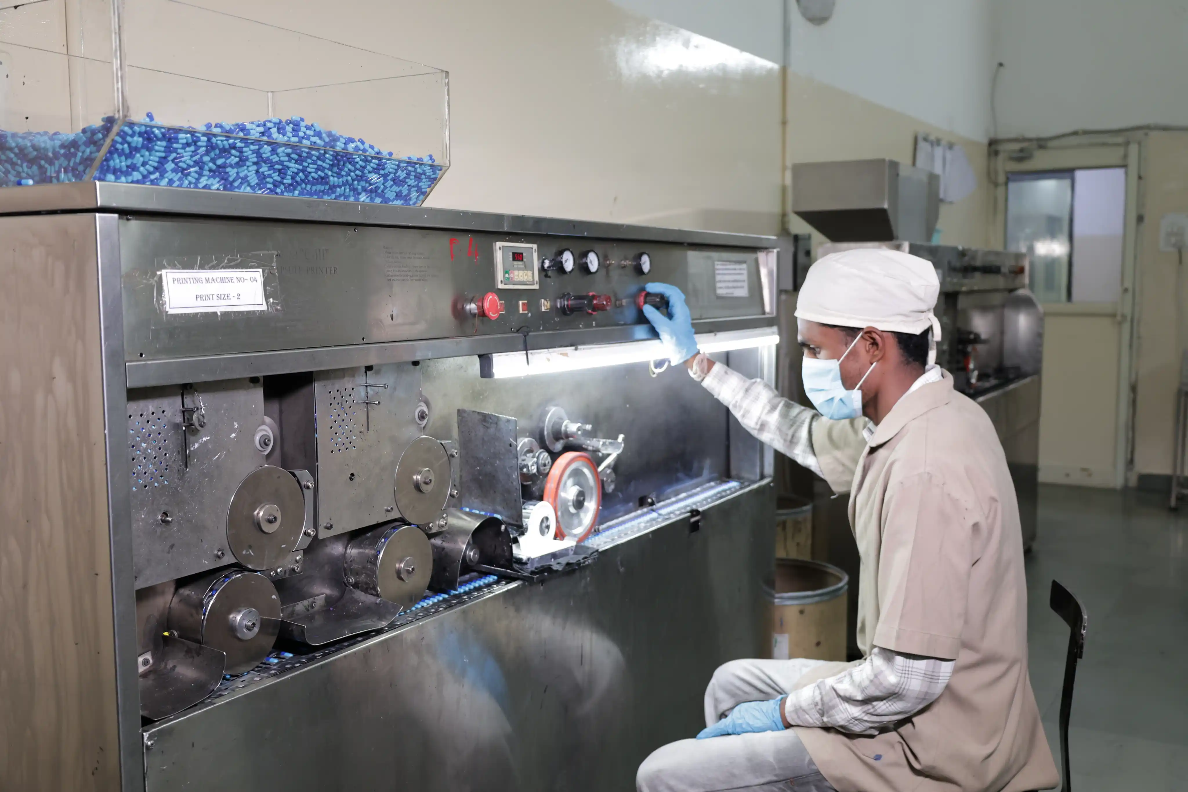 Gloved technician inspecting a capsule during quality control