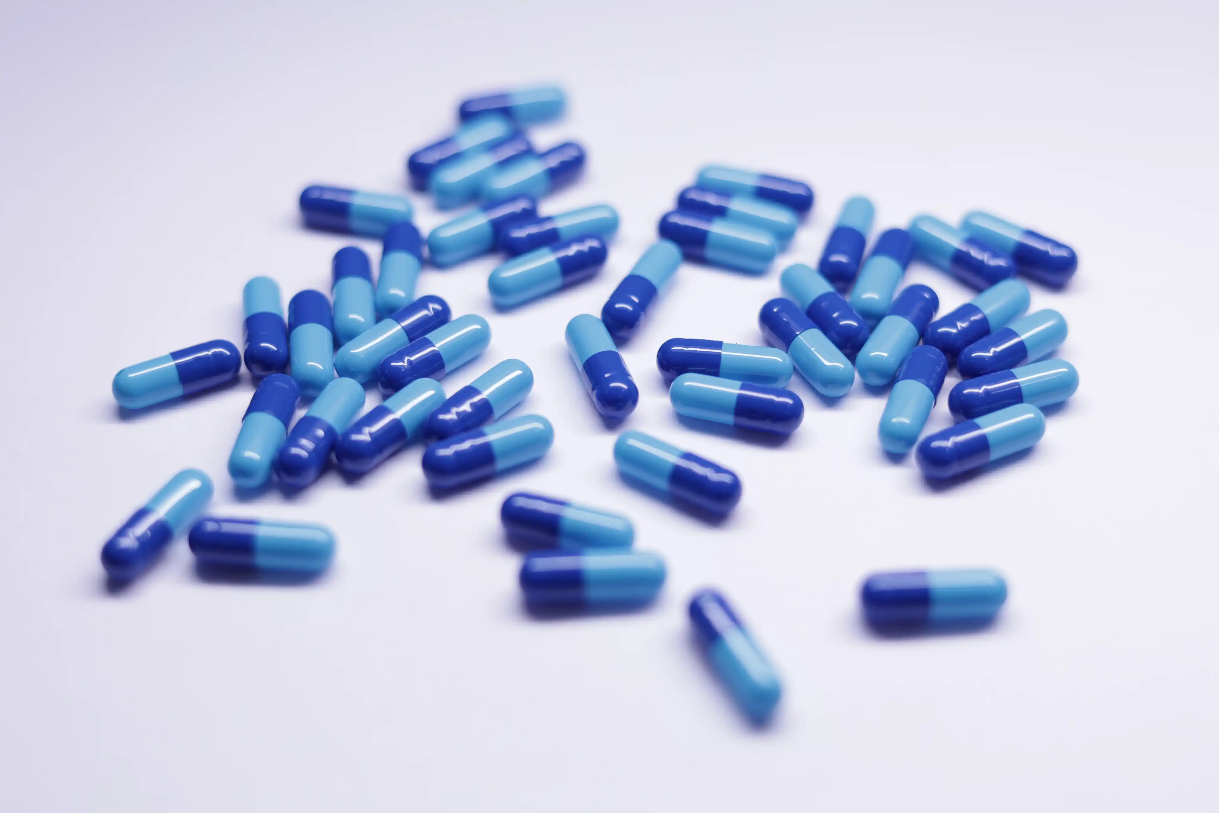 Red-and-white hard gelatin capsules on a dark surface