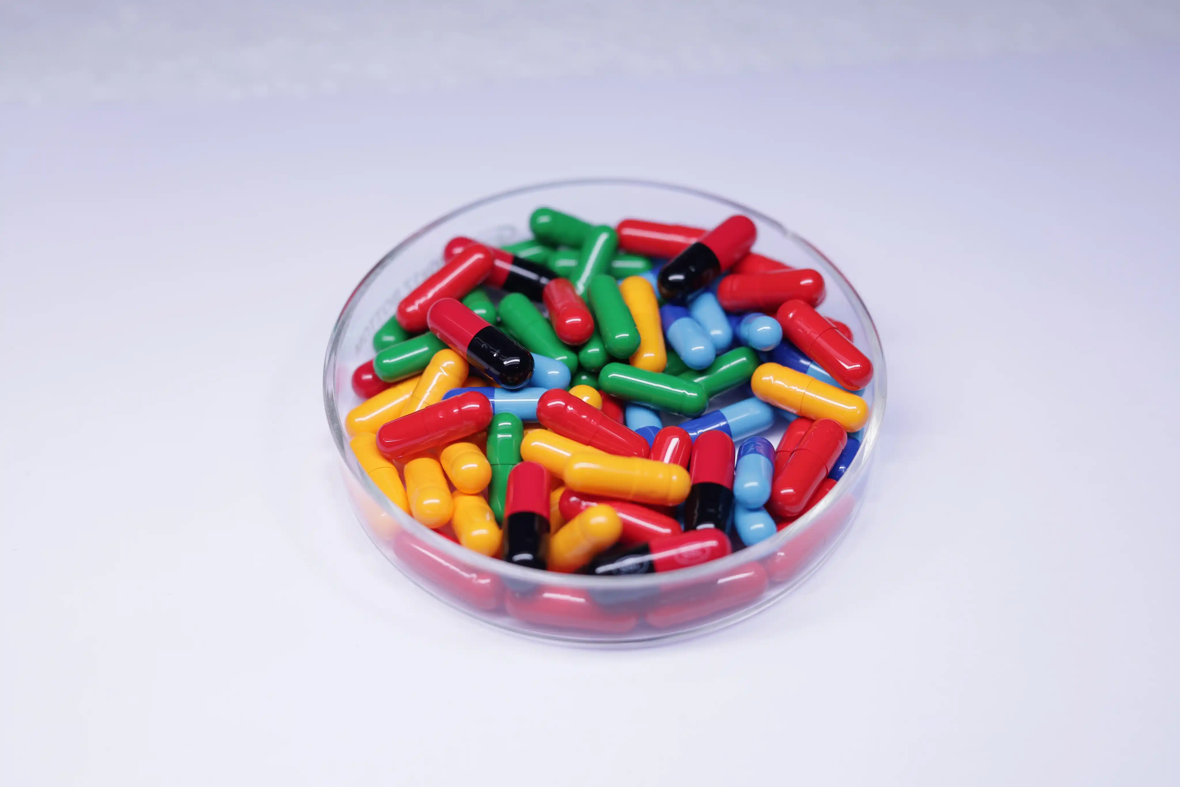 A bowl filled with brightly coloured hard gelatin capsules